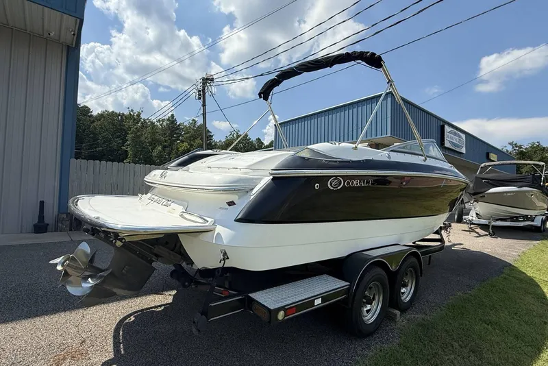 Slide: The Image of 2005 Cobalt 240 boat on trailer, parked outside a blue building under a clear sky. - 4