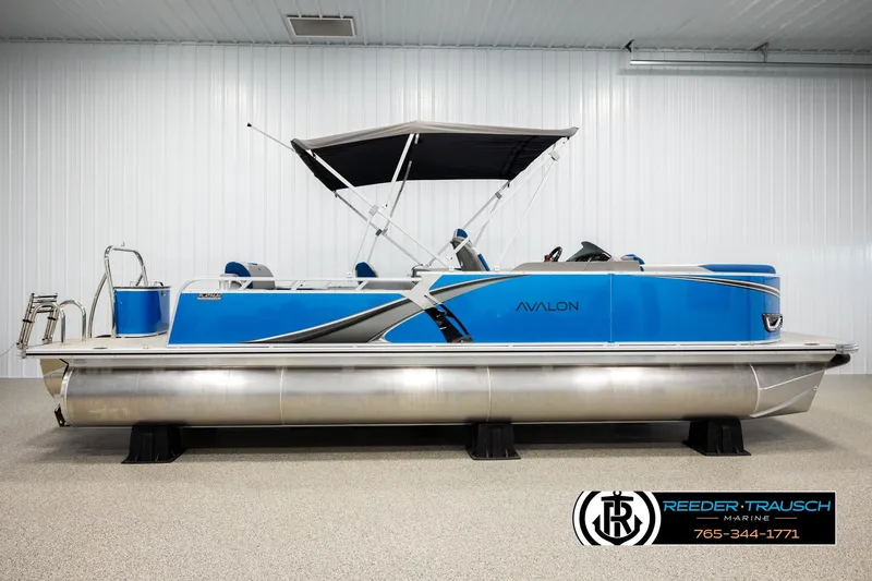 Slide: The Image of 2026 Avalon LSZ Vrl pontoon boat in showroom, featuring sleek blue design and canopy. - 5
