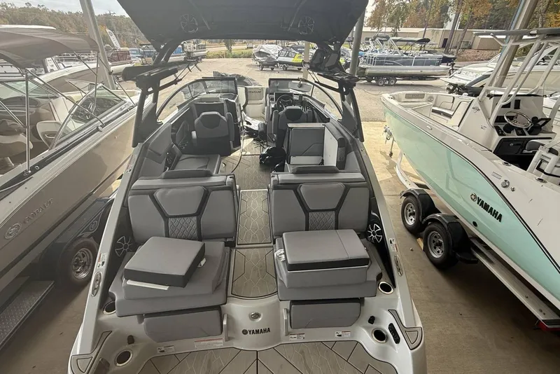 Slide: The Image of 2024 Yamaha Boats 255XD interior with modern seating and sleek design in a showroom. - 8