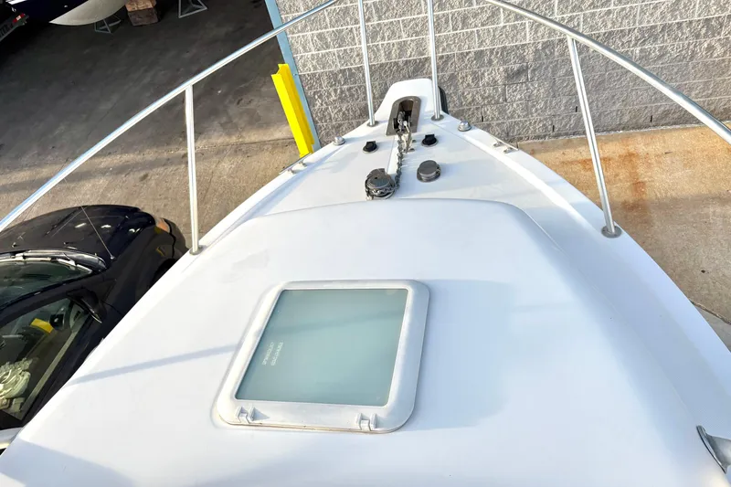 Slide: The Image of 2006 Century 2400 Walkaround boat deck with anchor and hatch, docked near a vehicle. - 6
