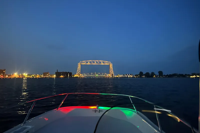 Slide: The Image of Boston Whaler 150 Super Sport 2014 cruising towards illuminated bridge at dusk. - 11