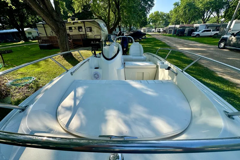 Slide: The Image of 2014 Boston Whaler 150 Super Sport boat interior with seating, parked in a grassy area. - 12