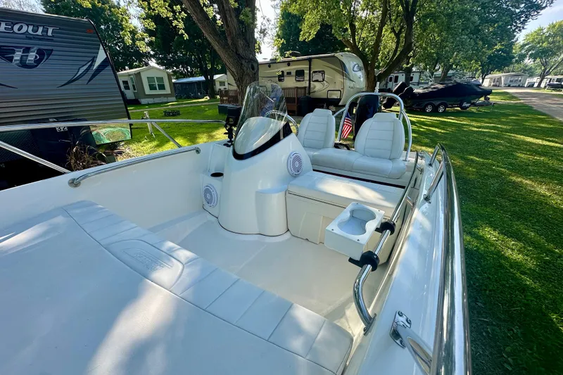 Slide: The Image of 2014 Boston Whaler 150 Super Sport boat interior with seating and cup holder, parked near RVs. - 13