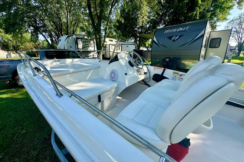 Slide: The Image of 2014 Boston Whaler 150 Super Sport boat interior with white seating, parked near RVs. - 15