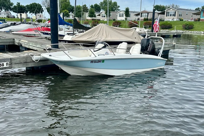 Slide: The Image of 2014 Boston Whaler 150 Super Sport docked at a marina, calm water, and nearby boats. - 5