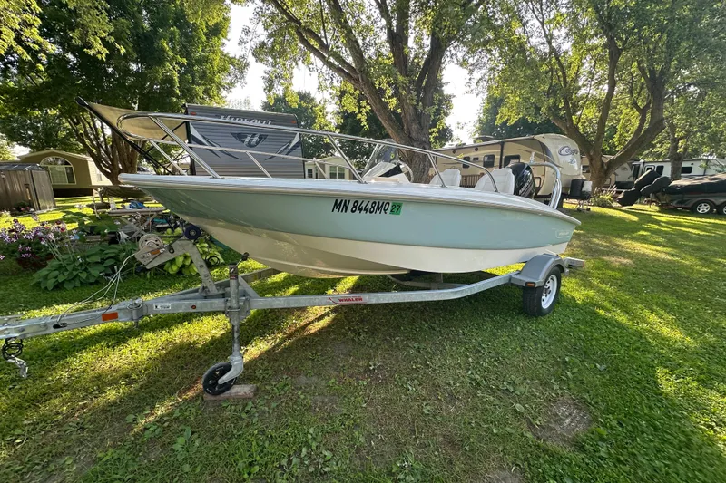 Slide: The Image of 2014 Boston Whaler 150 Super Sport boat on trailer, parked on grassy area. - 7