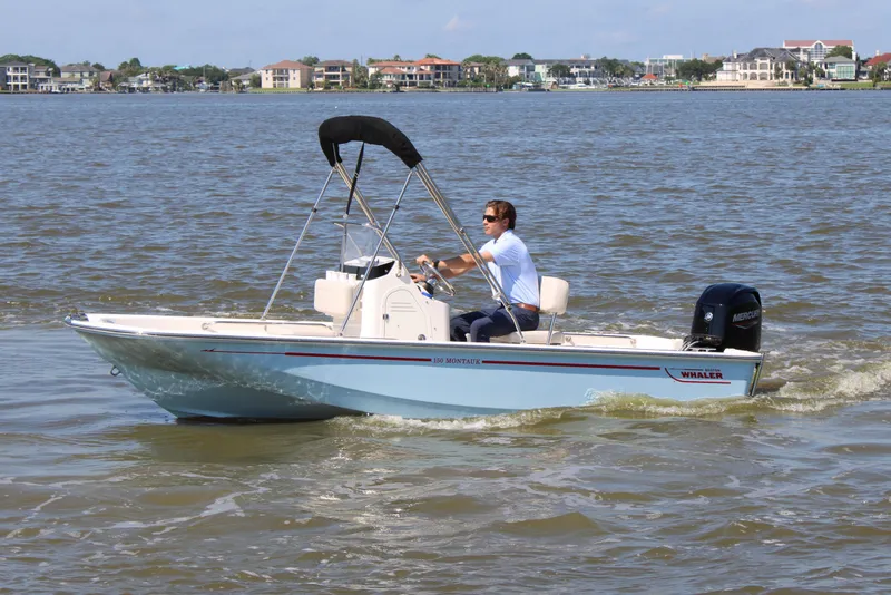 Slide: The Image of 2026 Boston Whaler 150 Montauk on calm water with driver. - 13