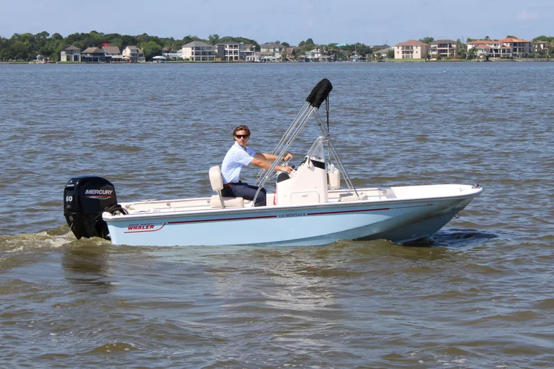 Slide: The Image of 2026 Boston Whaler 150 Montauk on water with driver. - 6