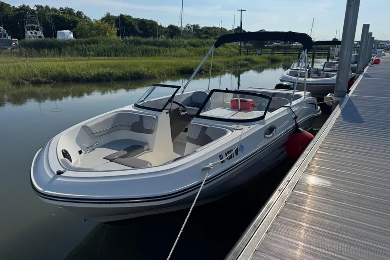 The Image of 2023 Bayliner VR6 Bowrider OB docked by a serene waterfront. - 0