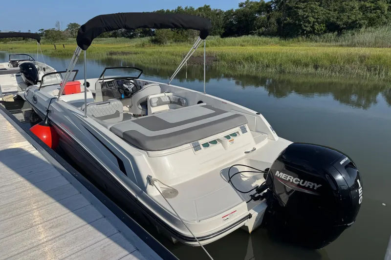 Slide: The Image of 2023 Bayliner VR6 Bowrider OB docked, featuring a Mercury outboard motor, in a serene waterway. - 3