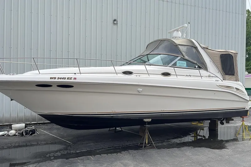 Slide: The Image of 2000 Sea Ray 340 Sundancer boat on stands, white exterior, docked indoors. - 14