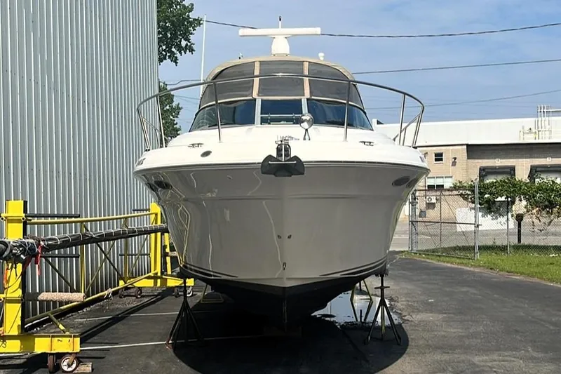 Slide: The Image of 2000 Sea Ray 340 Sundancer yacht on dry dock, front view, near industrial buildings. - 16