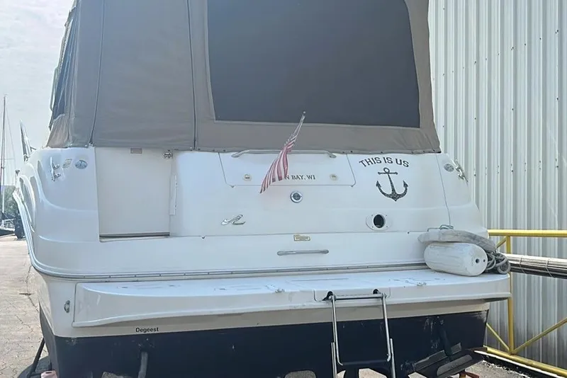 Slide: The Image of 2000 Sea Ray 340 Sundancer boat docked, rear view with cover and American flag. - 17