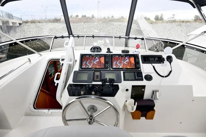 Slide: The Image of Control panel of a 2001 Symbol Raised Pilothouse Motoryacht with navigation screens and steering wheel. - 25