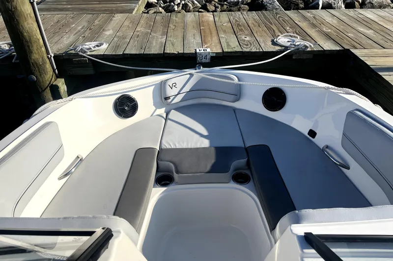 Slide: The Image of 2023 Bayliner VR6 Bowrider OB interior with gray seating, docked at wooden pier. - 8