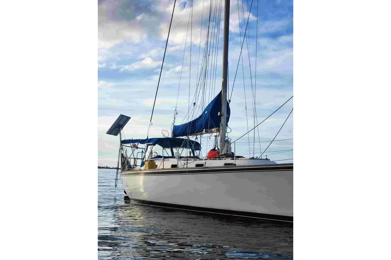 Slide: The Image of 1979 Tartan T 37 sailboat with blue sails on calm water under cloudy sky. - 1