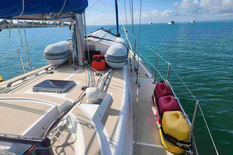 Slide: The Image of 1979 Tartan T 37 sailboat deck with lifeboats and fuel containers on calm water. - 10