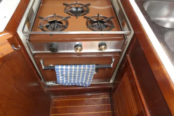 Slide: The Image of 1979 Tartan T 37 yacht kitchen with a three-burner stove and checkered towel. - 31