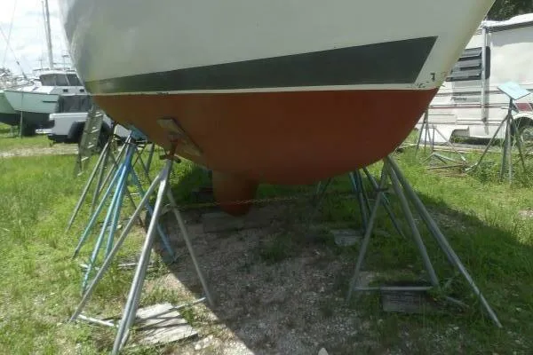 Slide: The Image of 1979 Tartan T 37 sailboat on stands, showing hull and keel in a grassy yard. - 38