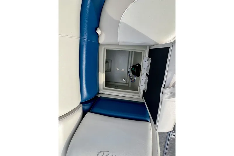 Slide: The Image of 2018 Manitou 23 Aurora LE boat seat storage compartment, featuring blue and white upholstery. - 18