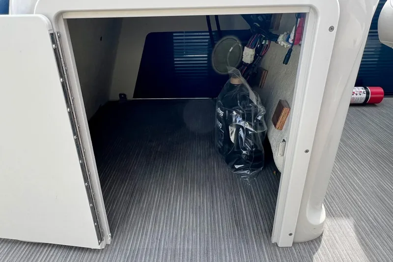 Slide: The Image of Storage compartment in 2018 Manitou 23 Aurora LE boat, featuring interior equipment and fire extinguisher. - 24