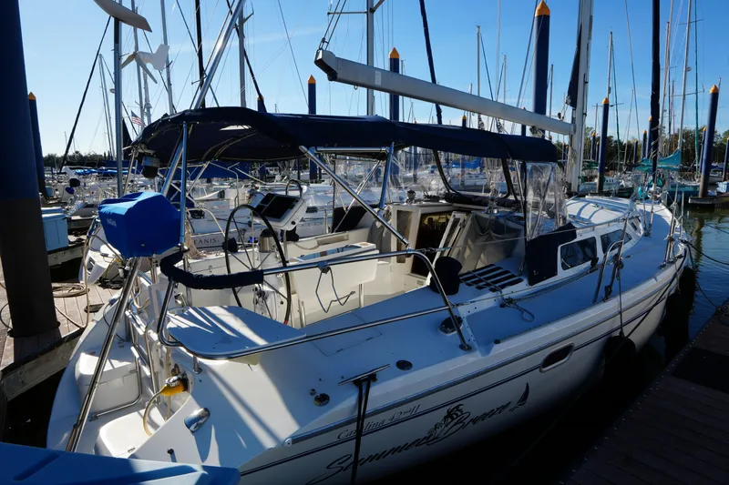 The Image of 2002 Catalina 42 Mark II sailboat docked at marina, featuring spacious cockpit and blue canopy. - 0