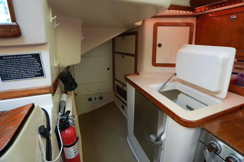 Slide: The Image of Interior of 2002 Catalina 42 Mark II sailboat kitchen with open fridge and wooden cabinetry. - 24