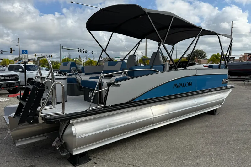 Slide: The Image of 2026 Avalon 2385 Catalina Quad Lounger, Tri Toon High Performance boat with canopy, parked outdoors. - 6
