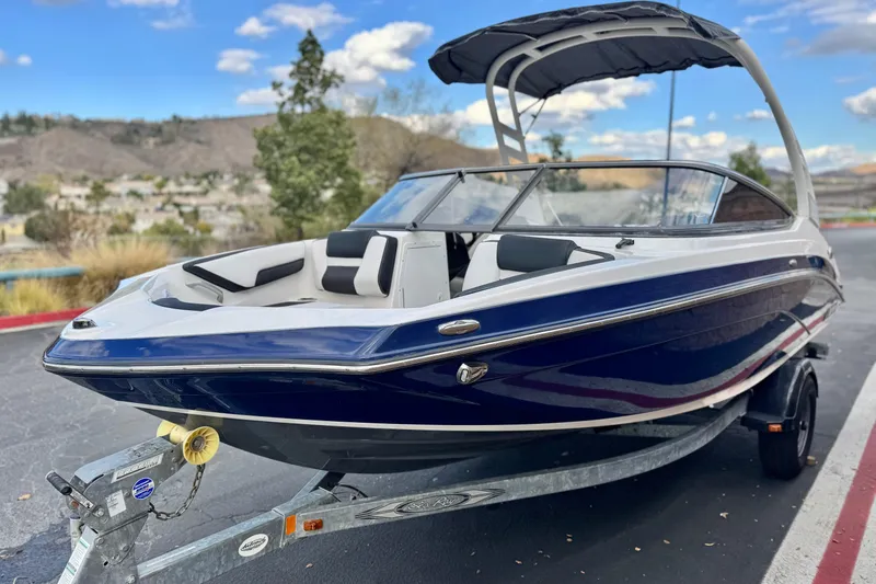 Slide: The Image of 2021 Yamaha Boats 195S on trailer, sleek design, blue and white exterior, outdoor setting. - 3