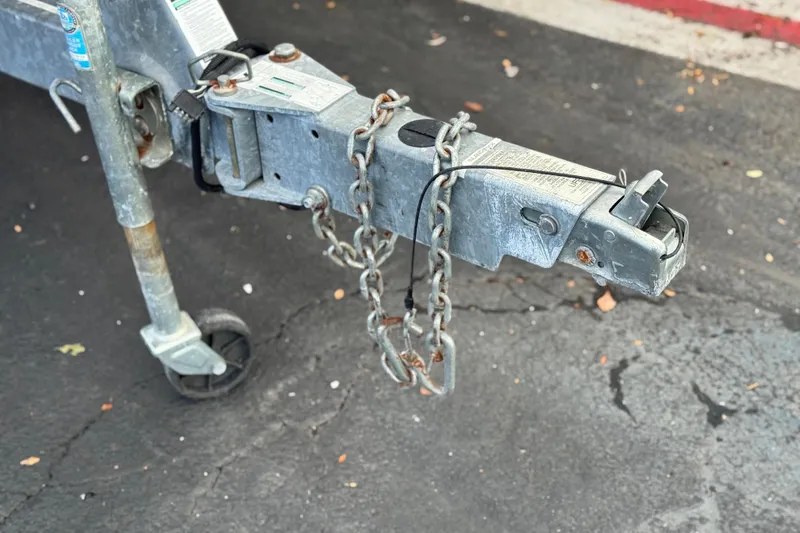 Slide: The Image of Trailer hitch of a 2021 Yamaha Boats 195S with safety chains on pavement. - 30