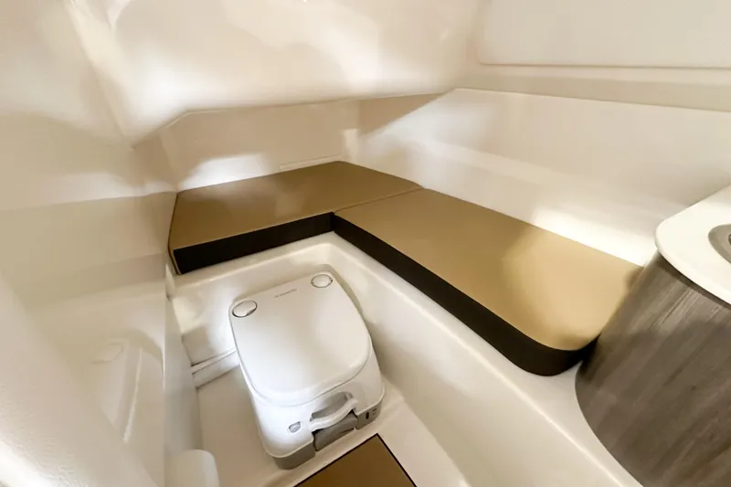 Slide: The Image of 2026 Sea Ray SDX 250 interior cabin with compact toilet and seating area. - 14
