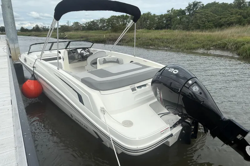 Slide: The Image of 2023 Bayliner VR6 Bowrider OB docked on a calm river with outboard motor. - 13
