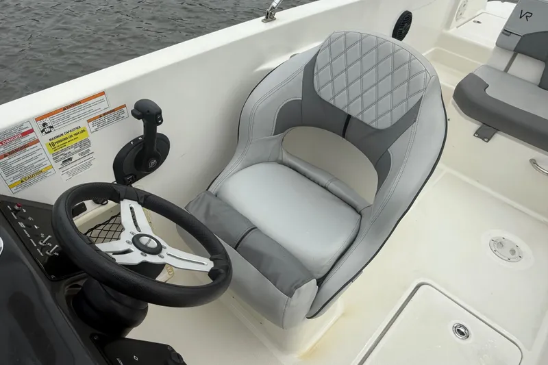 Slide: The Image of 2023 Bayliner VR6 Bowrider OB cockpit with steering wheel and cushioned seat. - 5