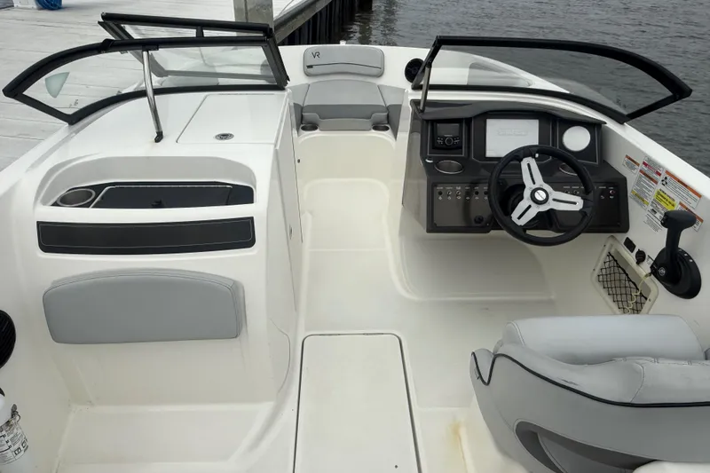 Slide: The Image of 2023 Bayliner VR6 Bowrider OB interior with steering wheel and seating, docked by water. - 7