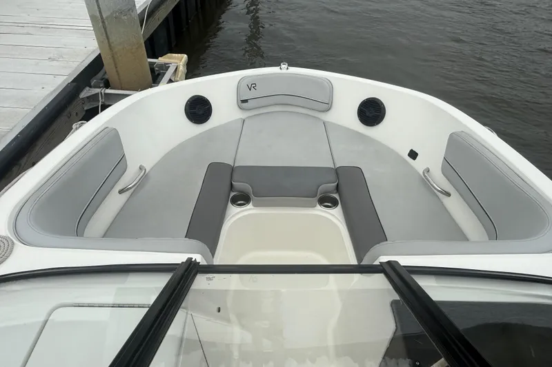 Slide: The Image of 2023 Bayliner VR6 Bowrider OB interior with gray seating and cup holders by the dock. - 9