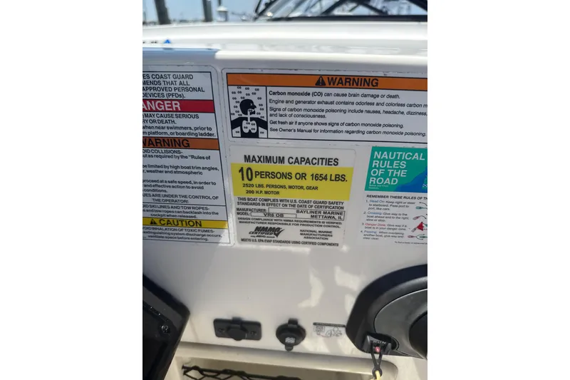 Slide: The Image of 2023 Bayliner VR6 Bowrider OB capacity and safety warning labels on dashboard. - 8