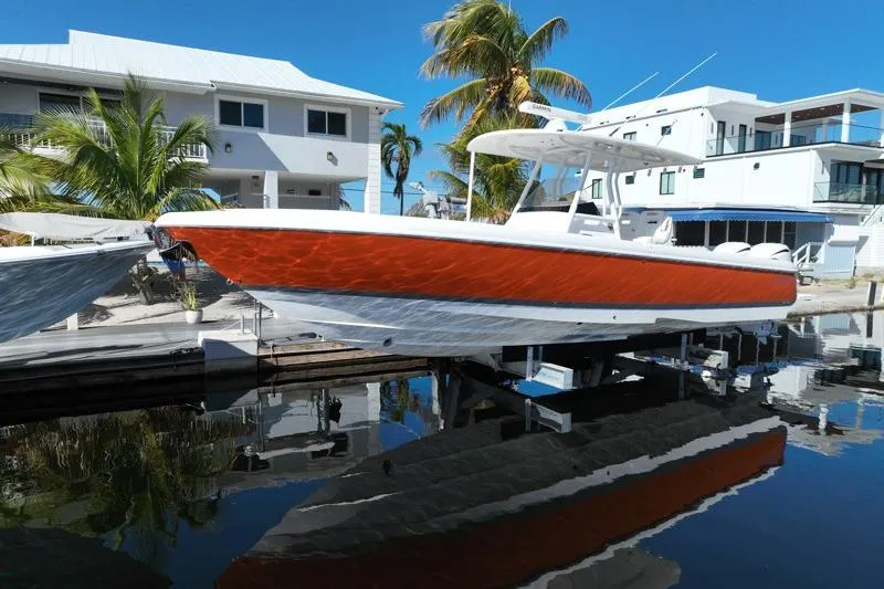 The Image of 2014 Intrepid 327 Center Console boat docked near waterfront homes and palm trees. - 0
