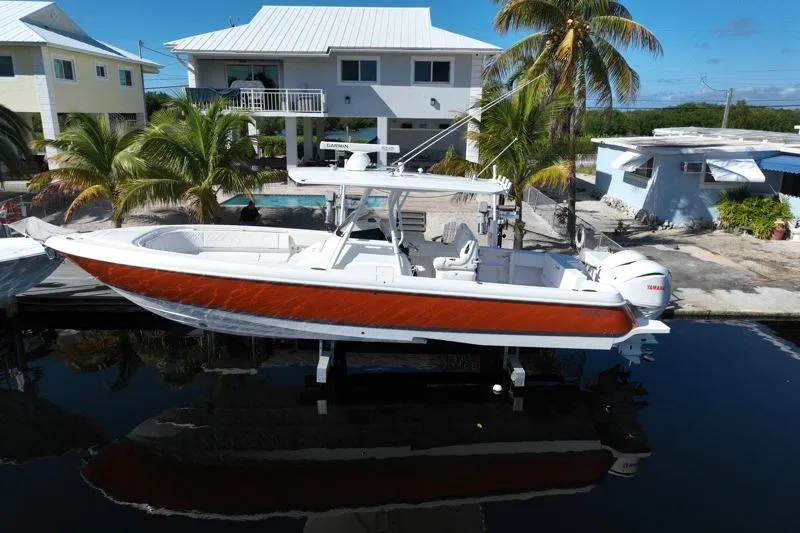 Slide: The Image of 2014 Intrepid 327 Center Console boat docked near waterfront homes and palm trees. - 1