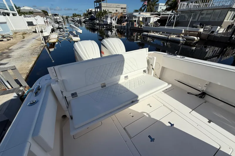 Slide: The Image of 2014 Intrepid 327 Center Console boat with seating, docked in a serene marina. - 11
