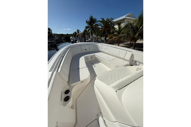 Slide: The Image of 2014 Intrepid 327 Center Console boat with spacious seating, docked near palm trees. - 17