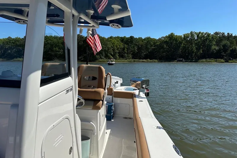 Slide: The Image of 2023 NauticStar 28 XS boat on a serene lake with American flag. - 6
