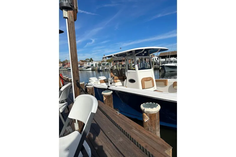 Slide: The Image of 2023 NauticStar 28 XS boat docked at a marina under a clear blue sky. - 7