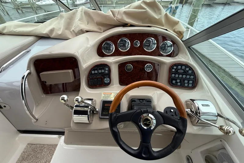 Slide: The Image of 2003 Sea Ray 320 Sundancer helm with gauges, controls, and wooden steering wheel. - 16