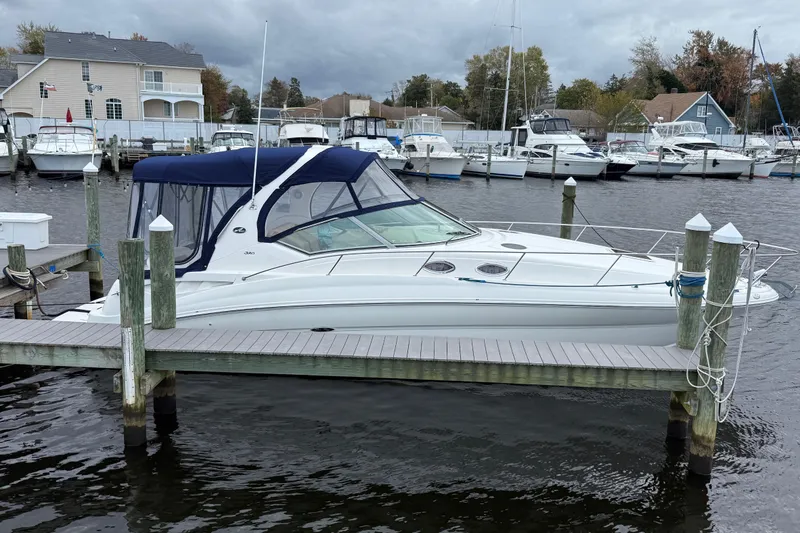 Slide: The Image of 2003 Sea Ray 320 Sundancer docked at marina, overcast sky, surrounded by other boats. - 2