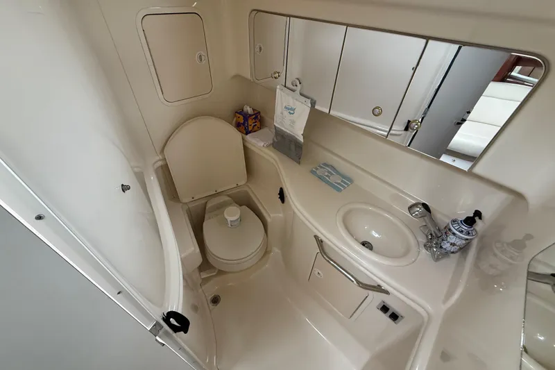 Slide: The Image of 2003 Sea Ray 320 Sundancer bathroom with toilet, sink, and storage cabinets. - 22
