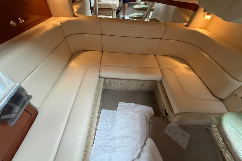 Slide: The Image of 2003 Sea Ray 320 Sundancer interior with beige leather seating and cozy cabin layout. - 24