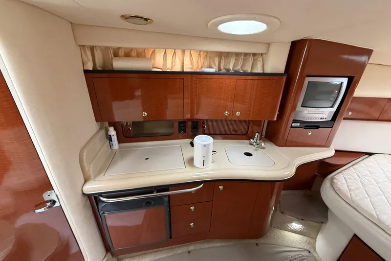 Slide: The Image of 2003 Sea Ray 320 Sundancer interior kitchen with wood cabinets and compact appliances. - 35