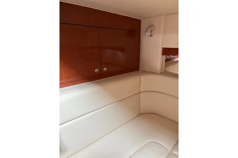 Slide: The Image of Luxurious interior of 2003 Sea Ray 320 Sundancer with white seating and wooden cabinets. - 45