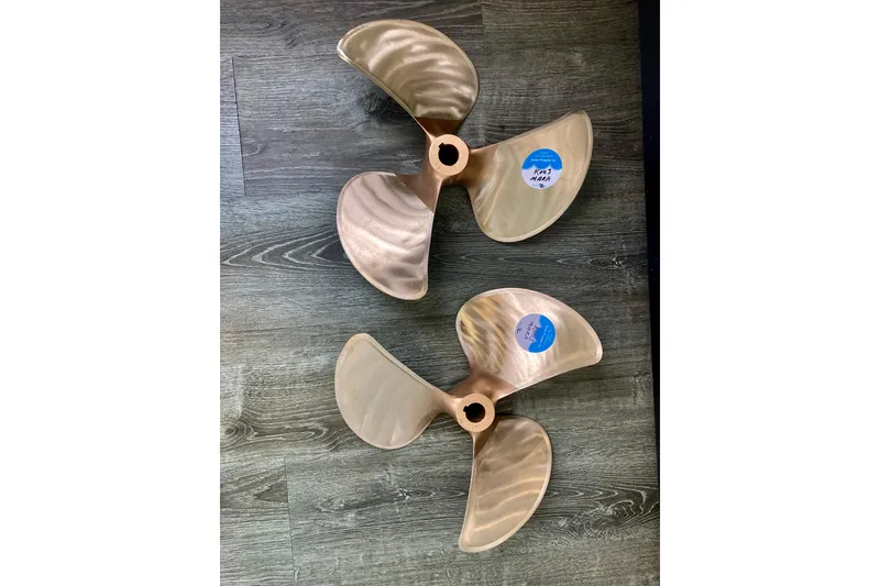 Slide: The Image of Two bronze boat propellers for 2003 Sea Ray 320 Sundancer on wooden floor. - 64