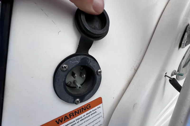 Slide: The Image of 2003 Wellcraft 29 CCF boat power outlet with warning label and protective cover. - 45